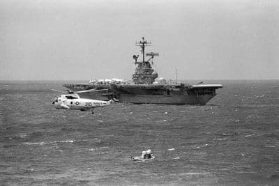 Velitelský modul Apolla 12 na hladině Pacifiku, letadlová loď USS Hornet a záchranný vrtulník (NASA).