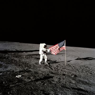 Astronaut Apolla 12 u vztyčené vlajky USA na povrchu Měsíce (NASA).