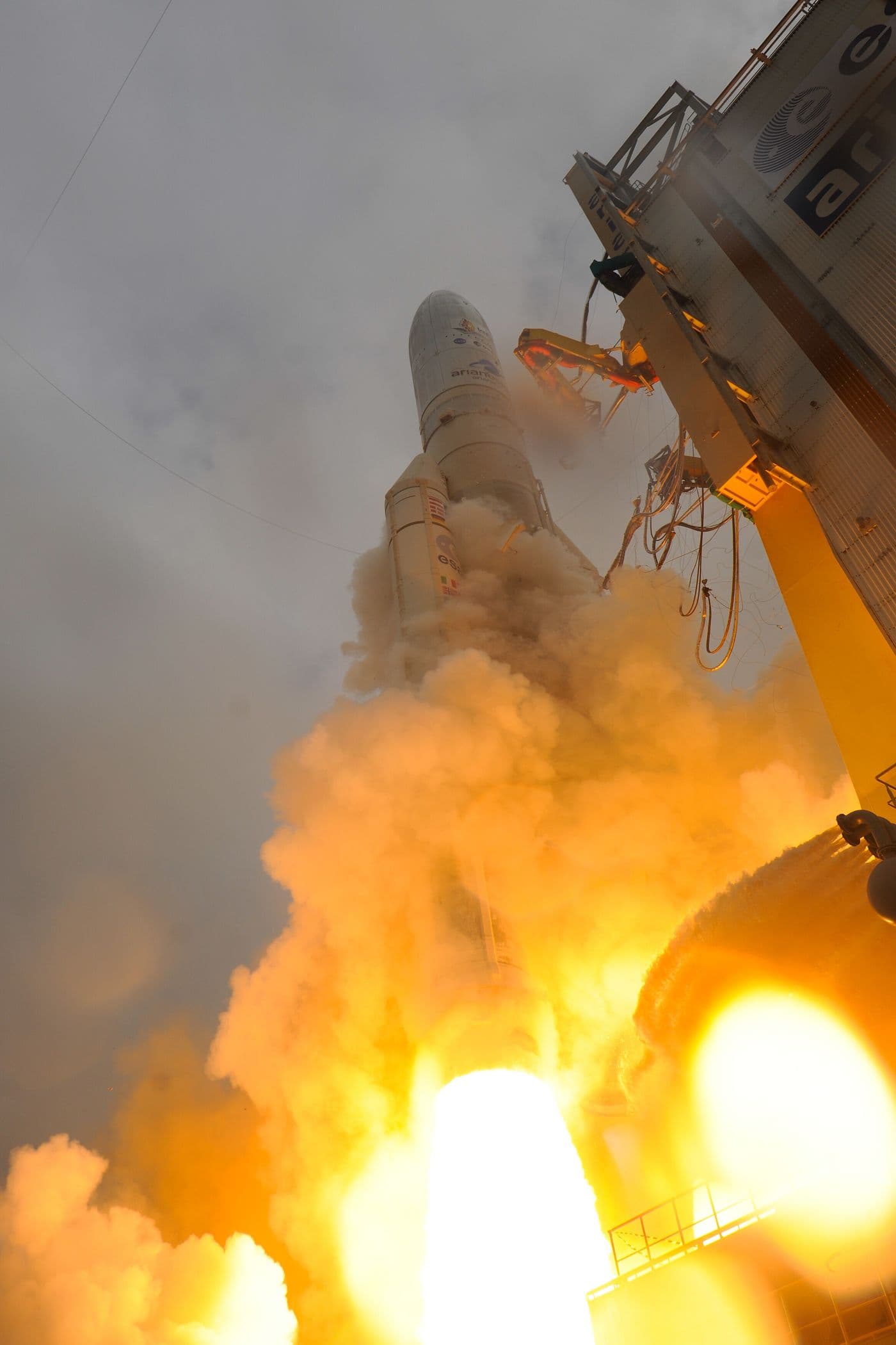 Start rakety Ariane 5 s vesmírným dalekohledem Jamese Webba — raketa se v oblaku ohně a kouře zvedá od startovní věže.